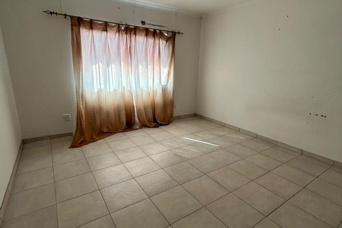 An empty bedroom featuring tiled flooring and neutral walls, ready for personalization and staging.