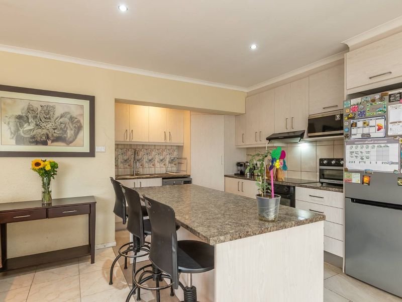A functional kitchen featuring laminate cabinetry, stone-look laminate countertops, a built-in oven, extractor fan, and a convenient breakfast island for casual dining.