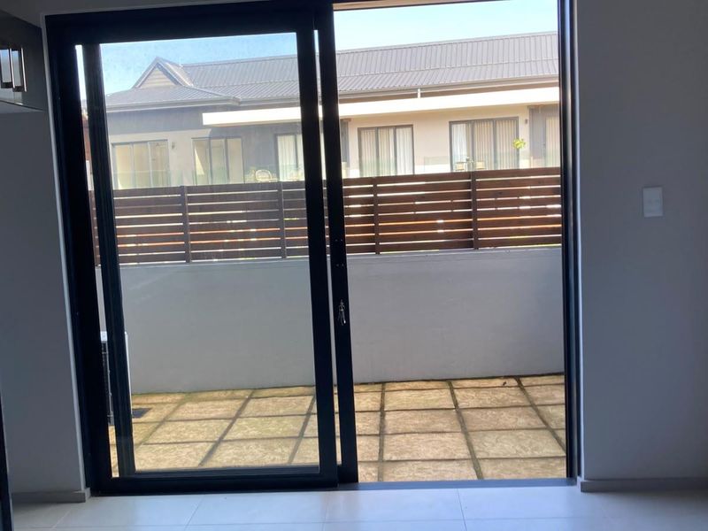 Open plan living area featuring modern tiled flooring and a large sliding glass door leading to a private paved patio area.
