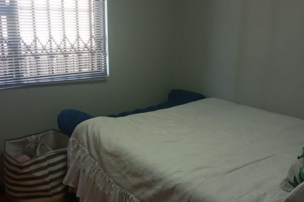 A standard bedroom featuring a window with venetian blinds and an integrated security gate.