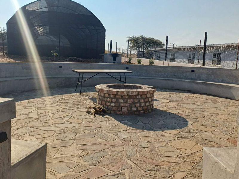 Outdoor entertainment area featuring a circular stone-paved patio with a built-in brick fire pit and integrated concrete bench seating.