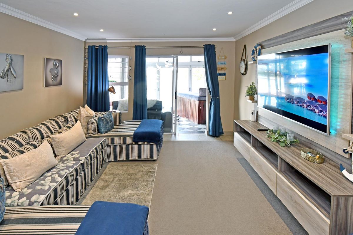 A well-maintained living room featuring recessed lighting, crown molding, and a built-in media console, with direct access to an outdoor patio area.