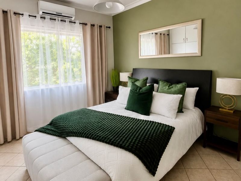 A well-maintained bedroom featuring tiled flooring, a split-system air conditioner, and a feature wall with a mounted mirror.