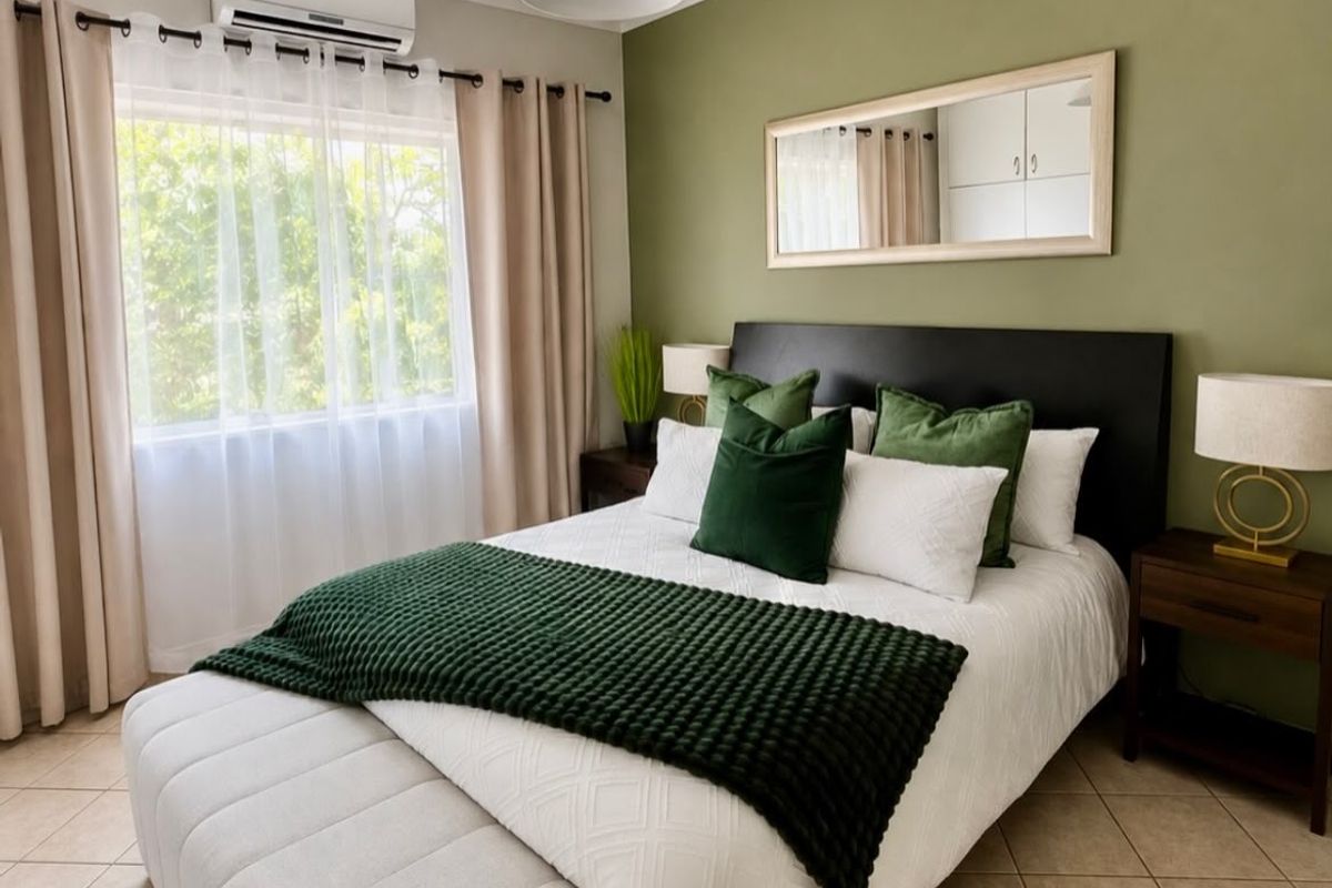 A well-maintained bedroom featuring tiled flooring, a split-system air conditioner, and a feature wall with a mounted mirror.