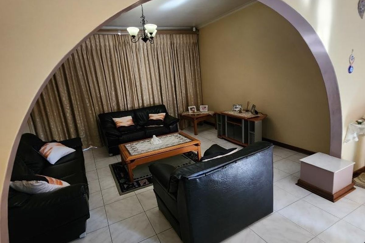 A living room area featuring tiled flooring and a prominent arched architectural opening connecting to the adjacent space.