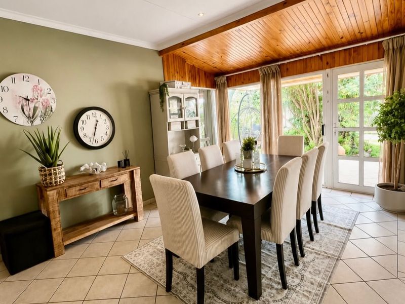 A bright dining room featuring tiled flooring, a warm timber-paneled ceiling, recessed lighting, and direct access to the garden through glass-paned french doors.
