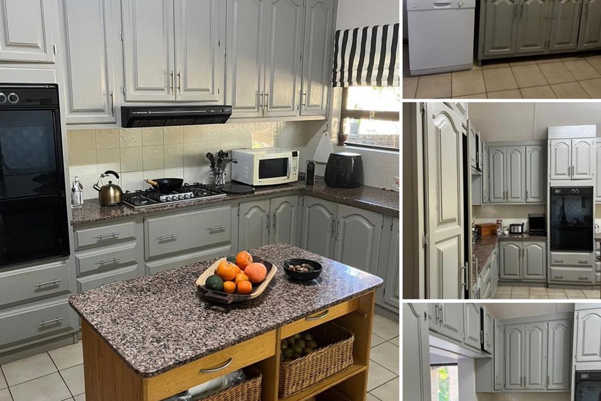 A kitchen featuring grey cabinetry, granite countertops, a built-in oven, and a gas hob, complemented by tiled flooring and a central island unit.
