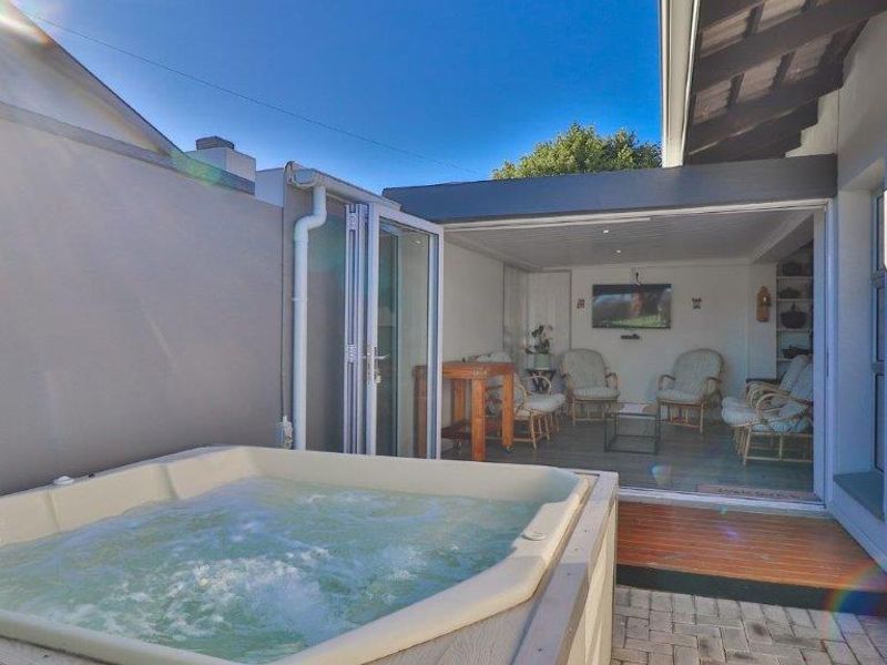 Outdoor entertainment area featuring a built-in jacuzzi, timber decking, and paved patio, seamlessly connected to the interior living space via bi-fold doors.