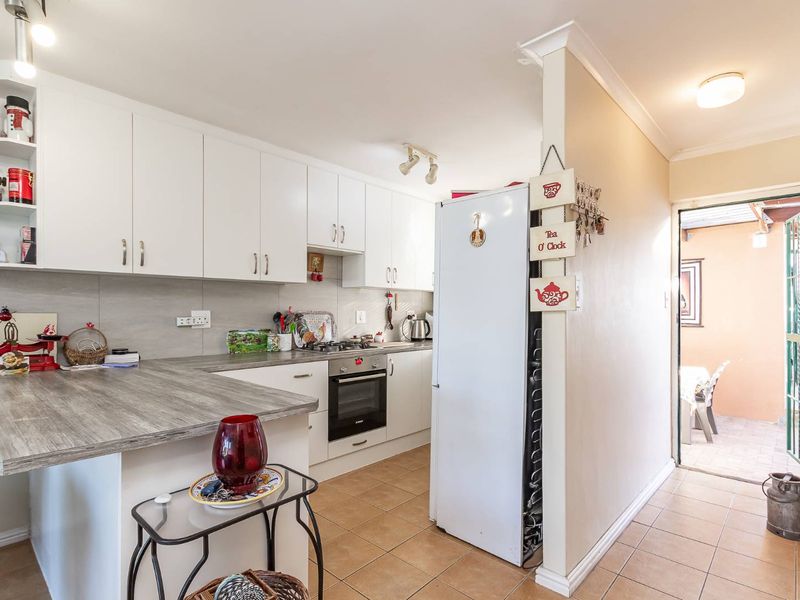 A functional kitchen featuring white cabinetry, wood-look laminate countertops, a built-in oven with gas hob, and tiled flooring, with direct access to an outdoor area.