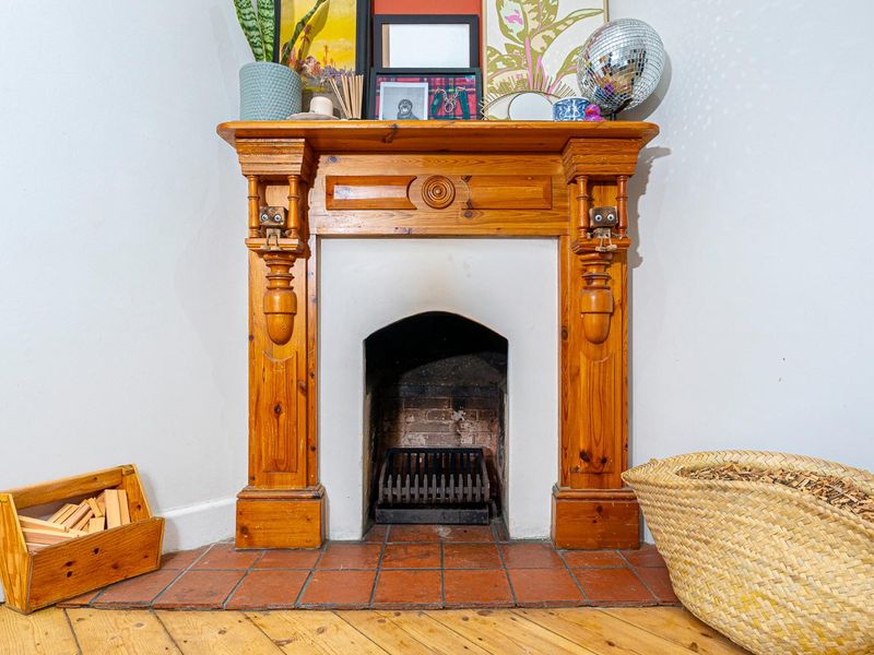 A traditional fireplace featuring a decorative wooden mantel and a tiled brick hearth, providing a classic focal point for the living area.