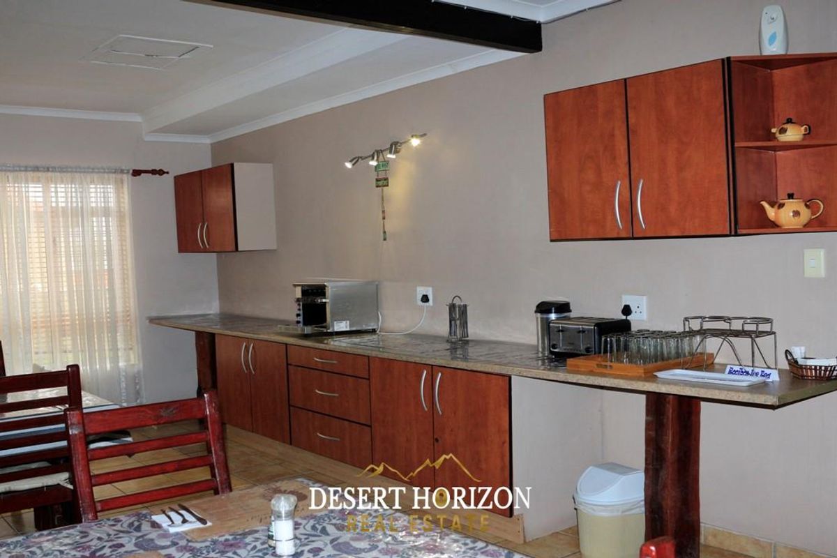 A functional kitchen area featuring wood-finish cabinetry, stone-look countertops, and integrated lighting, providing a practical space for meal preparation.