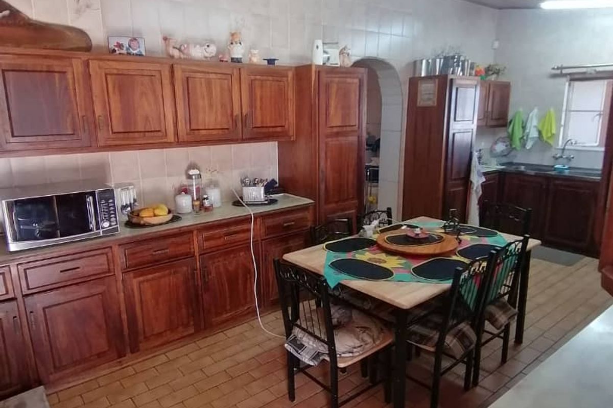 A spacious kitchen featuring wooden cabinetry, tiled walls, and a wood-paneled ceiling, offering a functional layout with an integrated dining area.