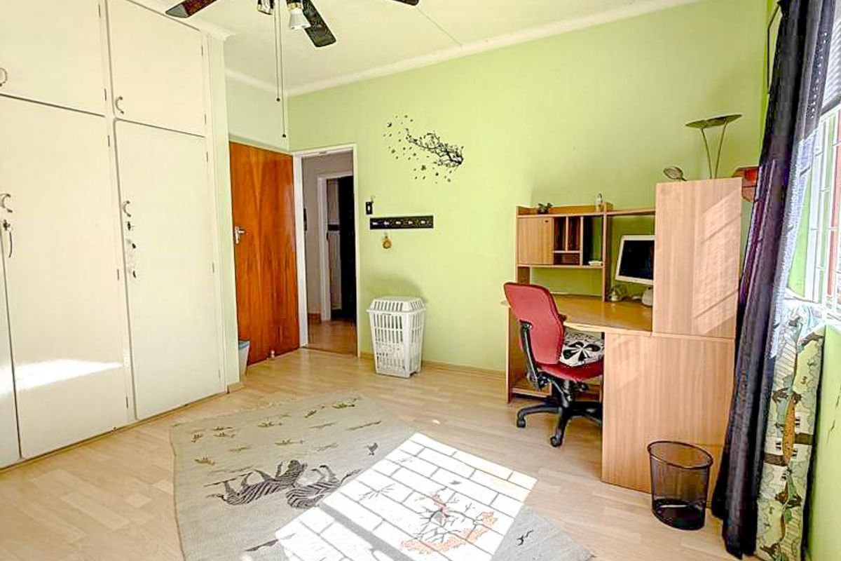 A bedroom featuring built-in cupboards, a ceiling fan, and laminate flooring.