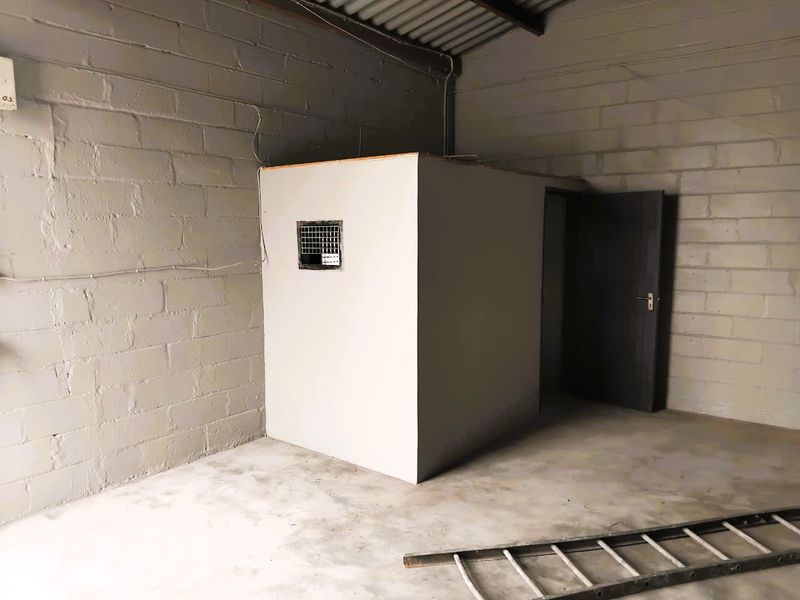 Industrial utility space featuring exposed concrete block walls, a corrugated metal roof, and a separate enclosed partition room with an internal door.