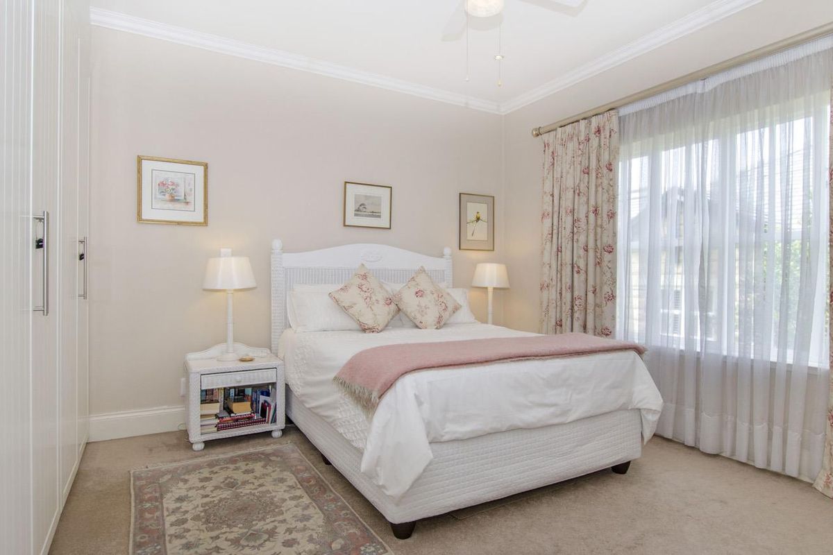 A well-maintained bedroom featuring built-in wardrobes, neutral carpeting, and a ceiling fan, offering a comfortable and functional living space.