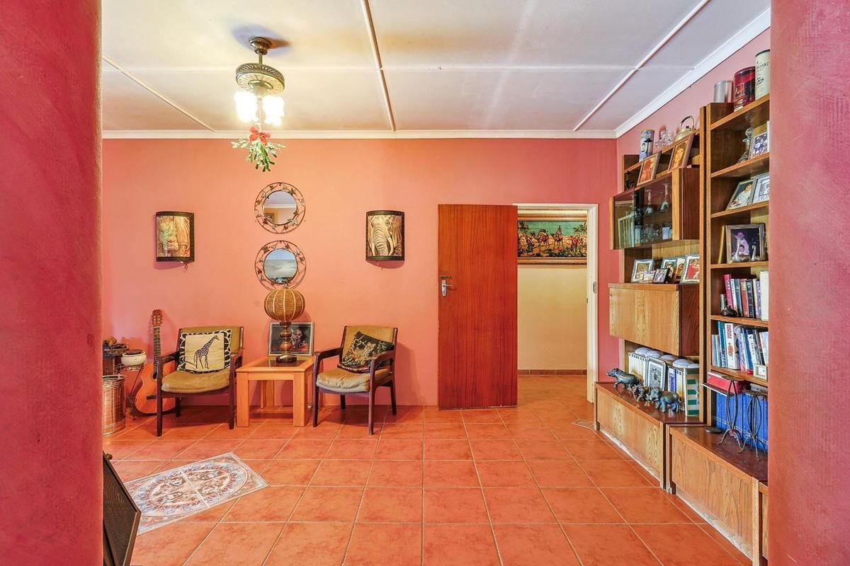 A living area featuring terracotta floor tiles, a wooden door, and a built-in shelving unit, providing a functional space with traditional finishes.