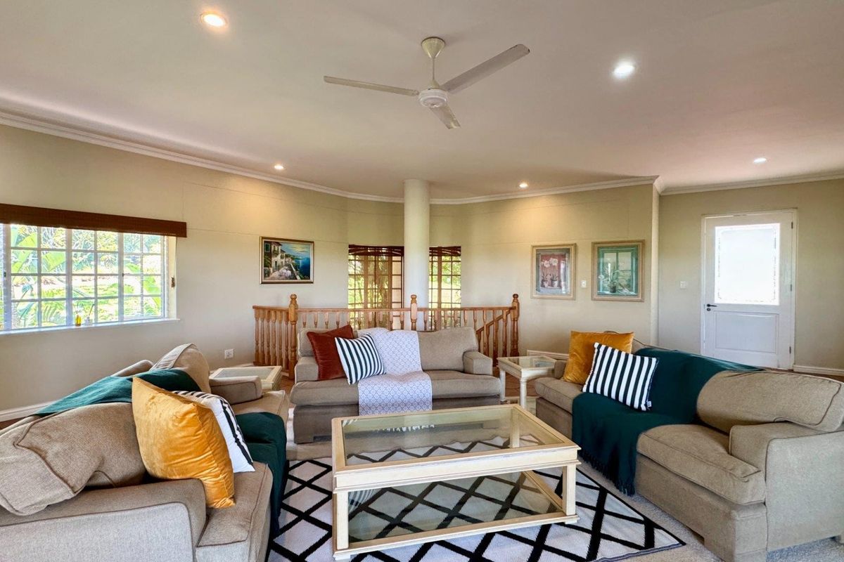 Spacious living room featuring a central structural column, timber balustrade, recessed downlights, and a ceiling fan, offering a comfortable and well-lit living area.