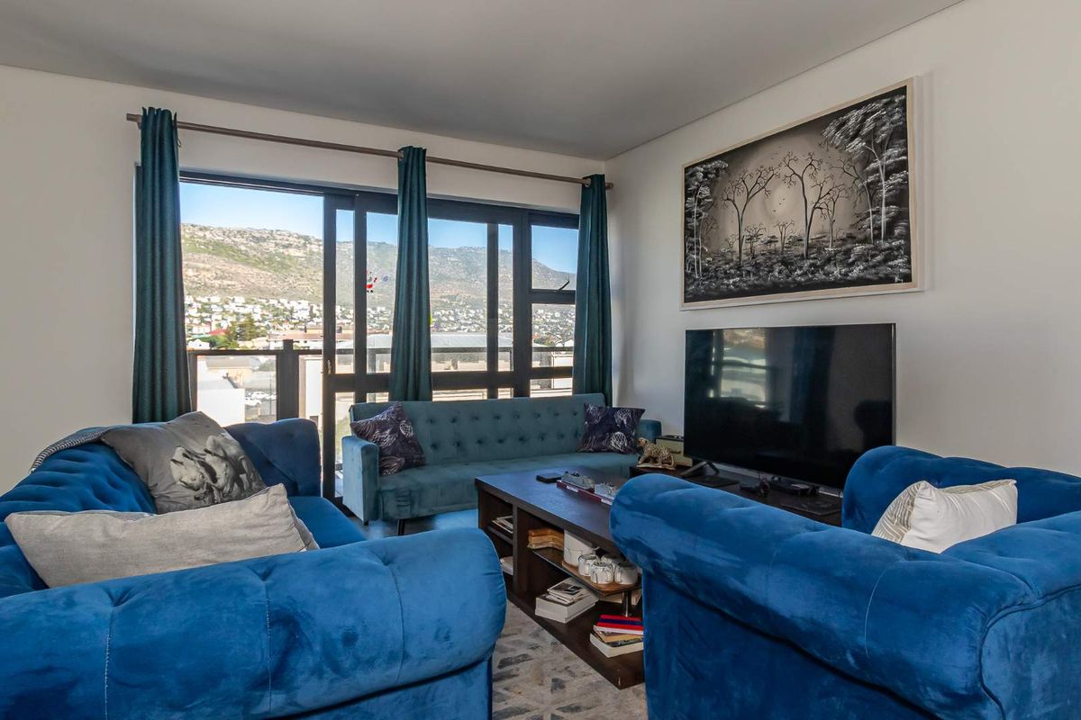 A bright living room featuring large sliding glass doors that provide access to a balcony and offer scenic mountain and neighborhood views.
