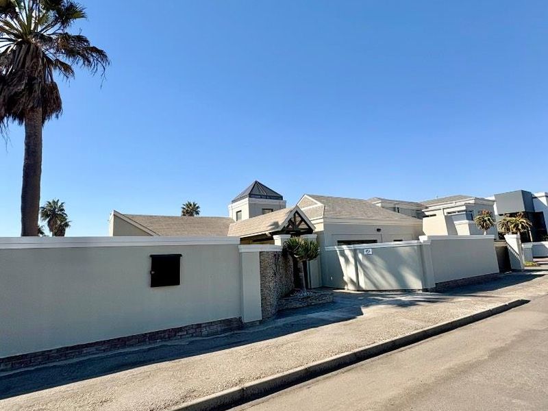 Front exterior view of the property featuring a secure perimeter wall, stone-clad entrance detail, and tiled roof structure.