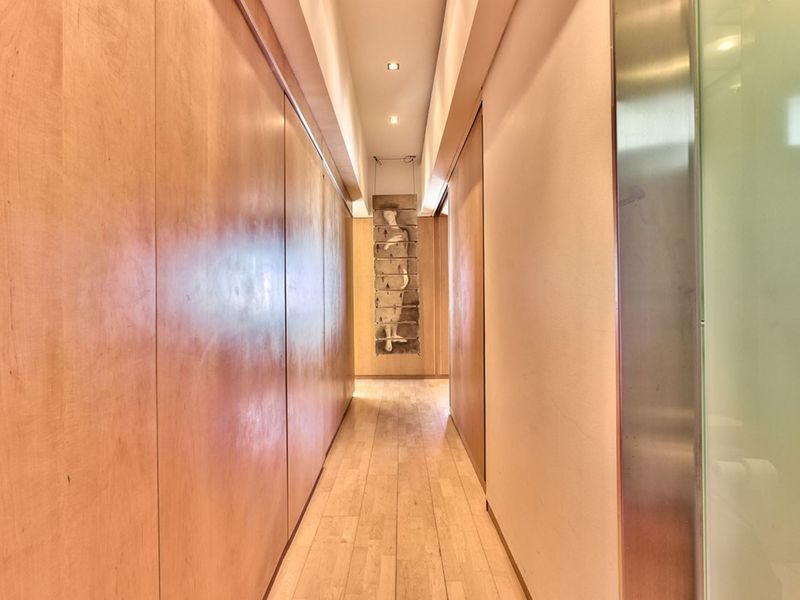 A modern, well-lit hallway featuring sleek wood paneling, hardwood flooring, and integrated recessed lighting, creating a clean and sophisticated transition space.