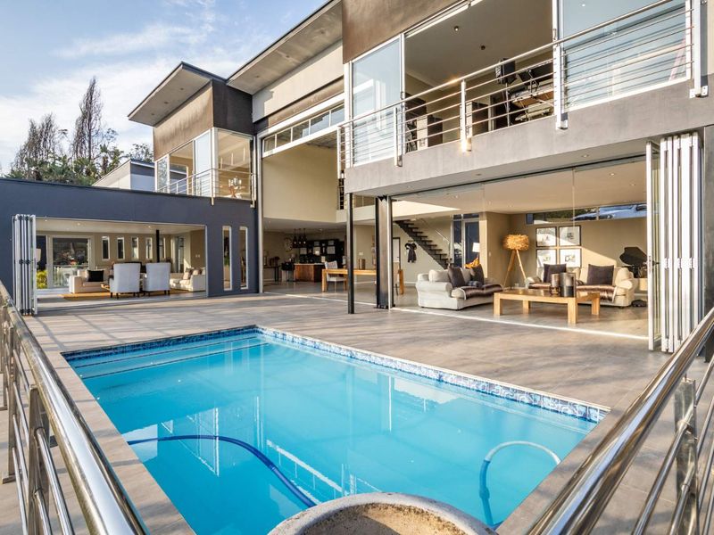 Modern luxury residence featuring a swimming pool, expansive tiled patio, and seamless indoor-outdoor flow through large bi-fold doors.