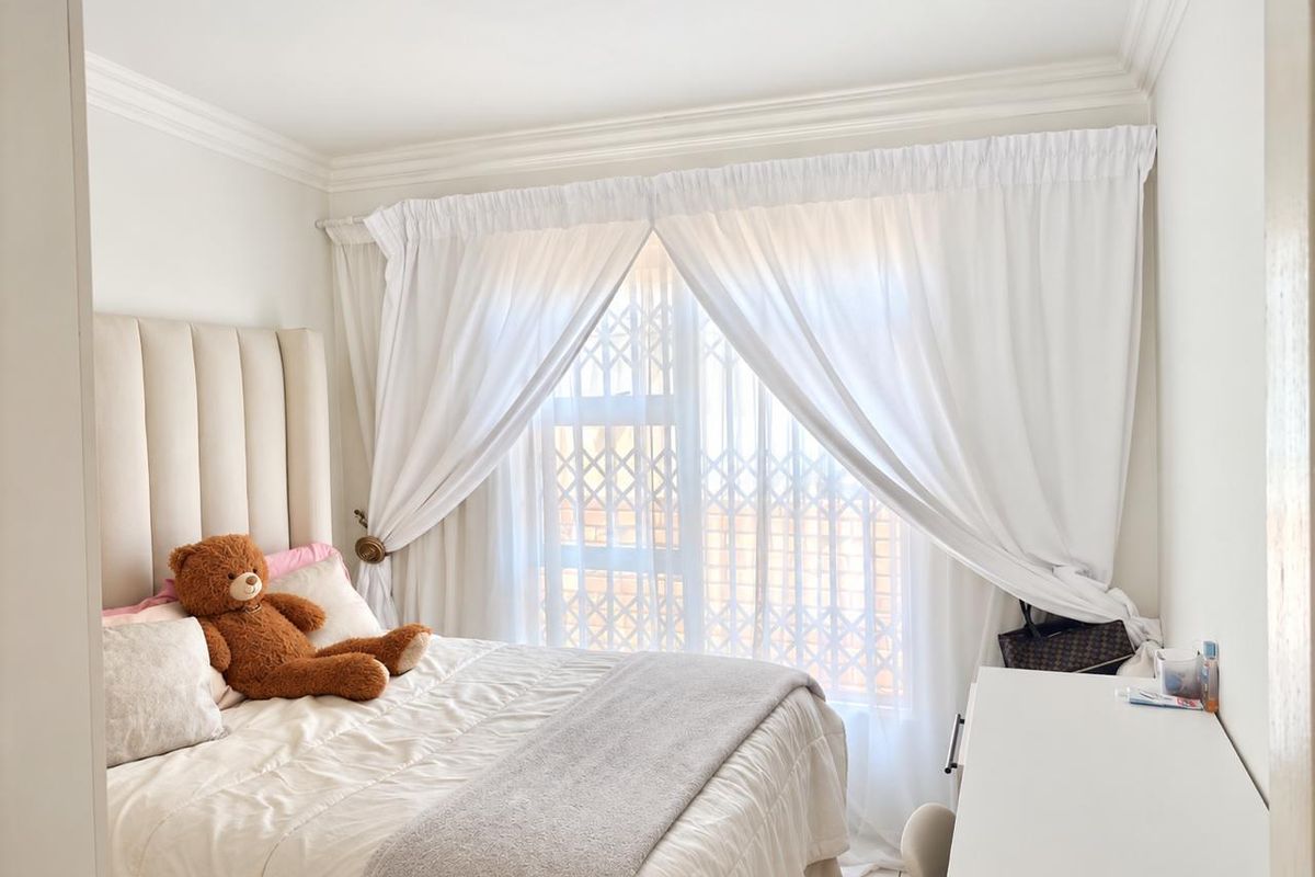 A bright and well-maintained bedroom featuring crown molding and a secure window with a fitted security gate.