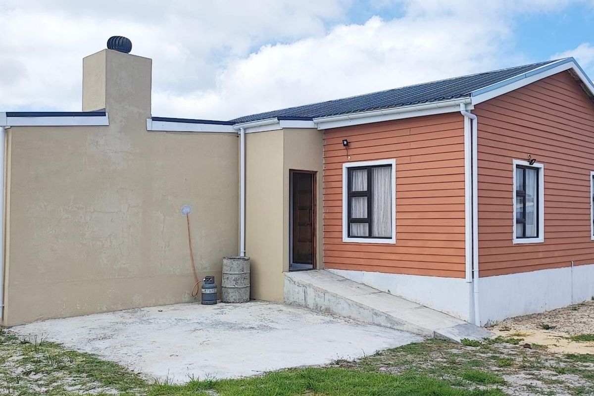 Rear view of the property featuring a concrete ramp, chimney, and a combination of plastered masonry and timber-look cladding finishes.