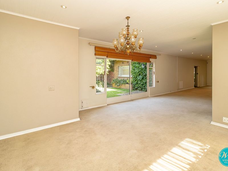 Spacious, light-filled living area featuring neutral carpeting, recessed lighting, and a large sliding glass door providing direct access to the rear garden.
