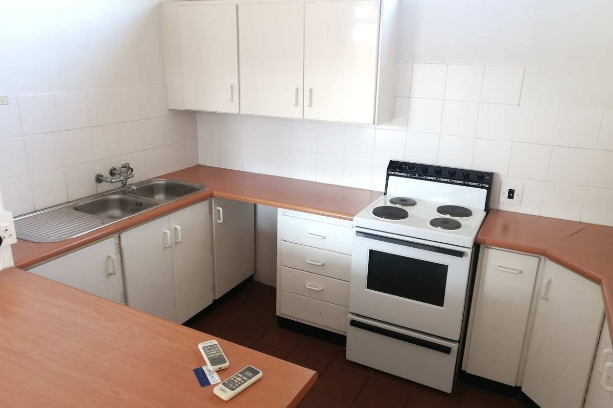 Functional kitchen featuring white cabinetry, laminate countertops, a double stainless steel sink, and a freestanding electric stove.