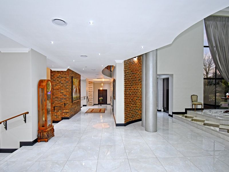 Spacious entrance hallway featuring polished porcelain tiles, exposed brick accents, and a grand staircase, creating an elegant and welcoming transition area.