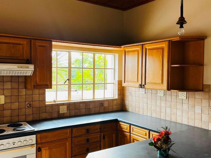 A functional kitchen featuring wooden cabinetry, dark countertops, tiled backsplash, and a distinctive wooden ceiling, offering a warm and traditional aesthetic.