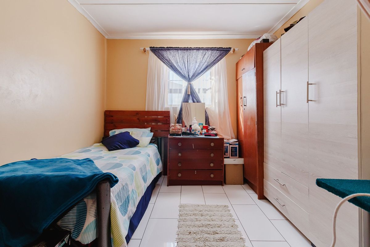 A functional bedroom featuring tiled flooring and a built-in wardrobe, offering a practical layout with natural light.