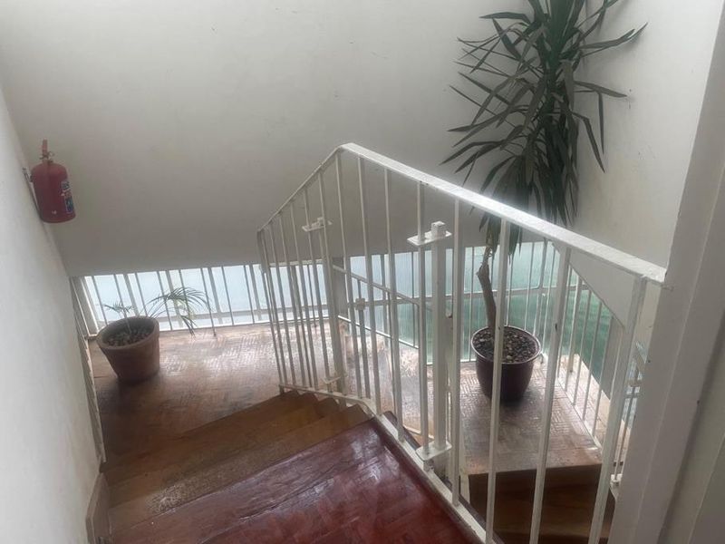 A functional interior staircase featuring parquet flooring and a white metal balustrade, providing access between levels in the apartment building.