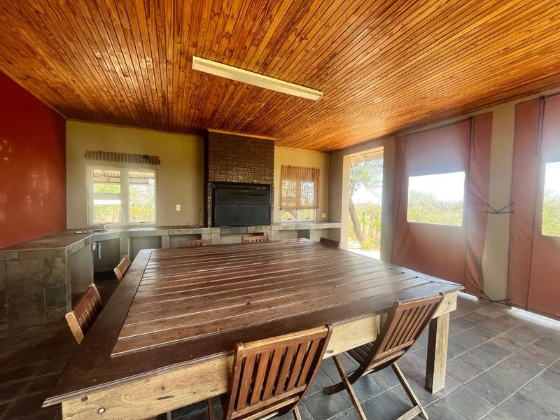 Covered outdoor patio featuring a built-in brick braai, tiled prep surfaces, timber ceiling, and durable tiled flooring, ideal for alfresco dining and entertaining.