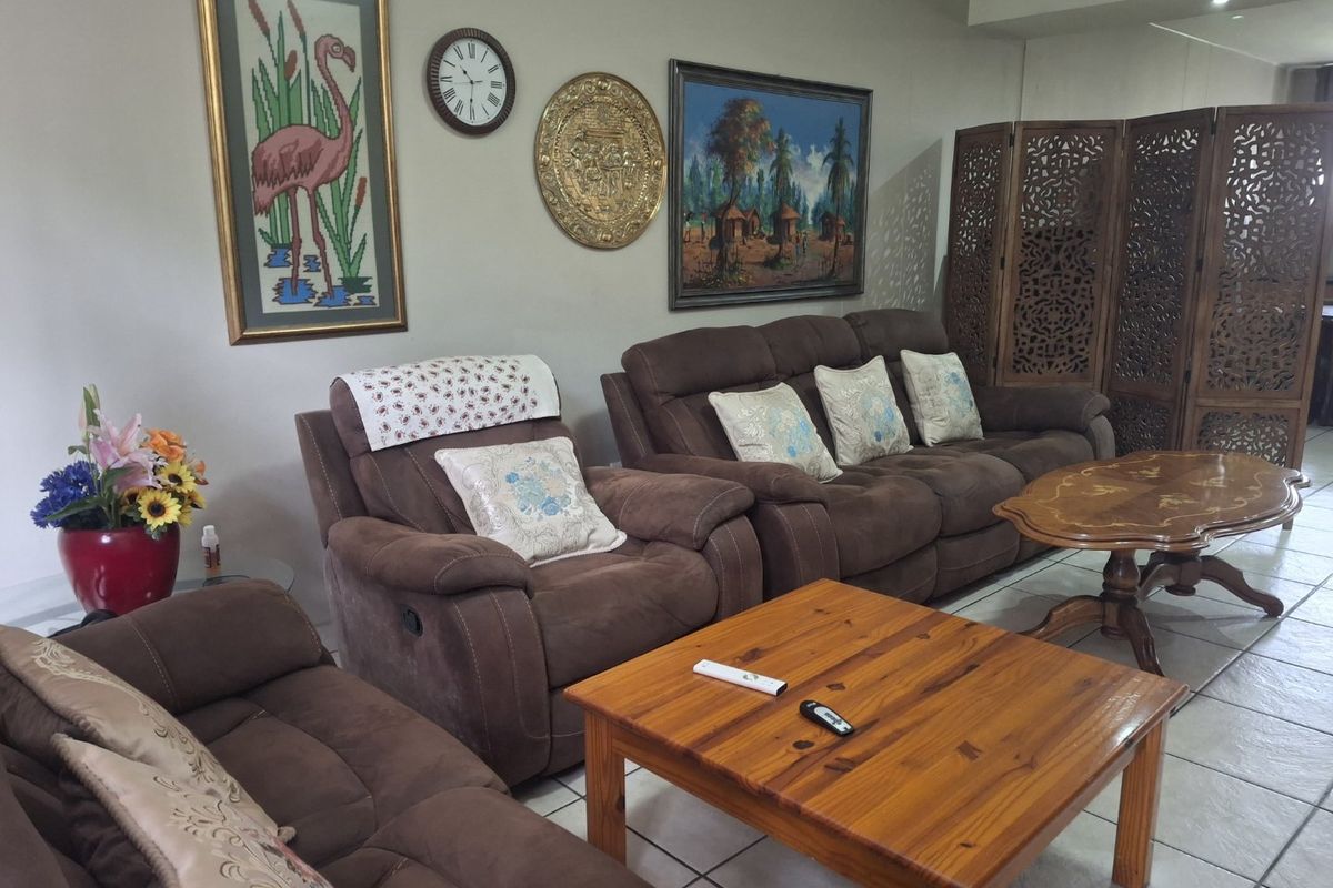 A comfortable living room area featuring neutral wall tones, tiled flooring, and recessed ceiling lighting, providing a functional space for relaxation.