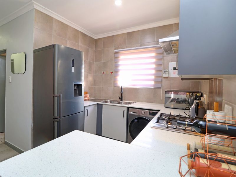 A modern kitchen featuring stone countertops, built-in cabinetry, a gas hob with extractor fan, and a tiled backsplash.