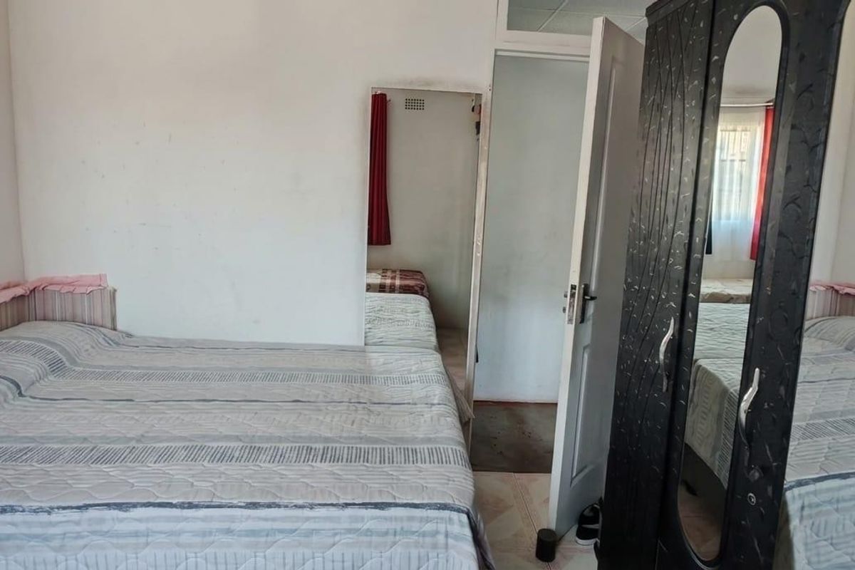 A bedroom featuring tiled flooring and a doorway leading to an adjacent space, requiring cosmetic updates to the wall finishes.