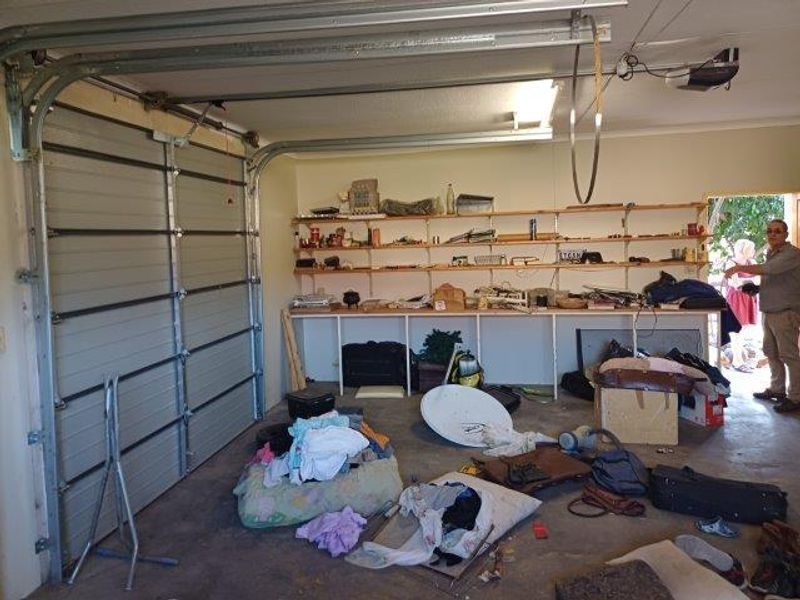 A functional garage space featuring a sectional door, overhead motor, and extensive built-in wall shelving for storage.