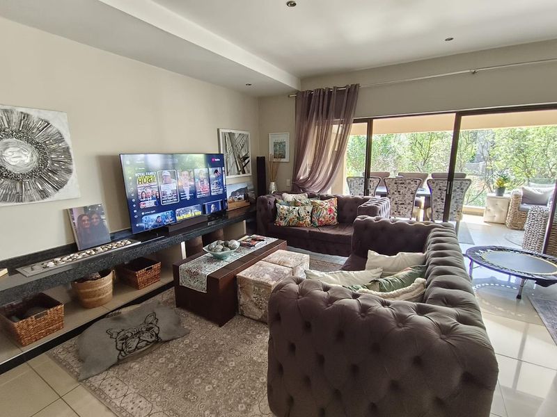 Spacious living room featuring a built-in stone media console, recessed ceiling lighting, and large sliding glass doors leading to an outdoor patio area.