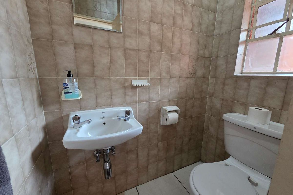 A compact guest bathroom featuring a wall-mounted basin, a standard toilet, and full-height wall tiling.