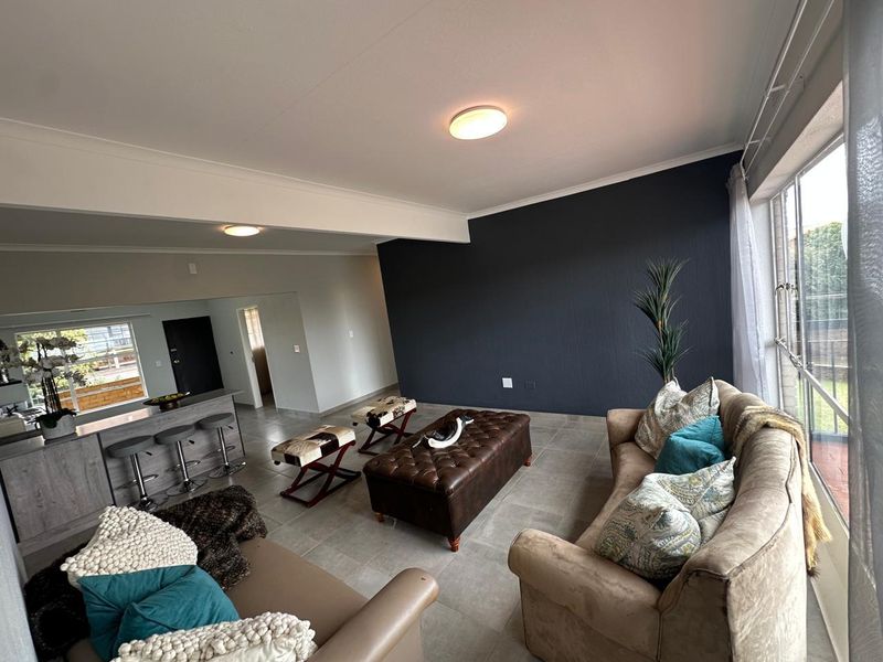 Spacious open-plan living area featuring tiled flooring, a breakfast bar, and large windows that provide ample natural light.