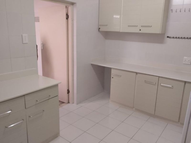 A functional scullery or utility area featuring built-in cabinetry, laminate countertops, and clean tiled finishes throughout.