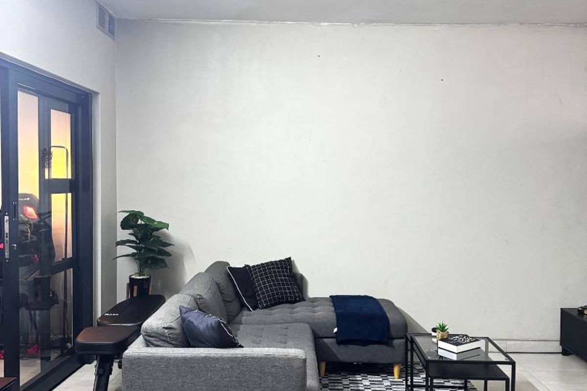 A bright living room featuring large glass sliding doors that provide access to an outdoor area, complemented by neutral tiled flooring throughout.
