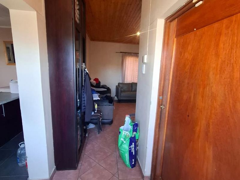 A functional hallway featuring tiled flooring and a timber-clad ceiling, providing access to adjacent living areas and storage.