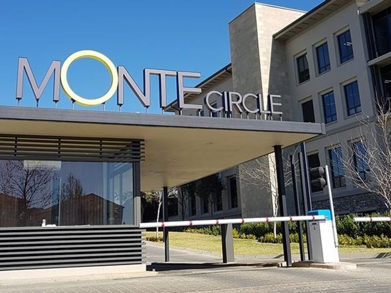 The main entrance to the Monte Circle office park, featuring a modern security guard booth, boom gate access, and professional signage.