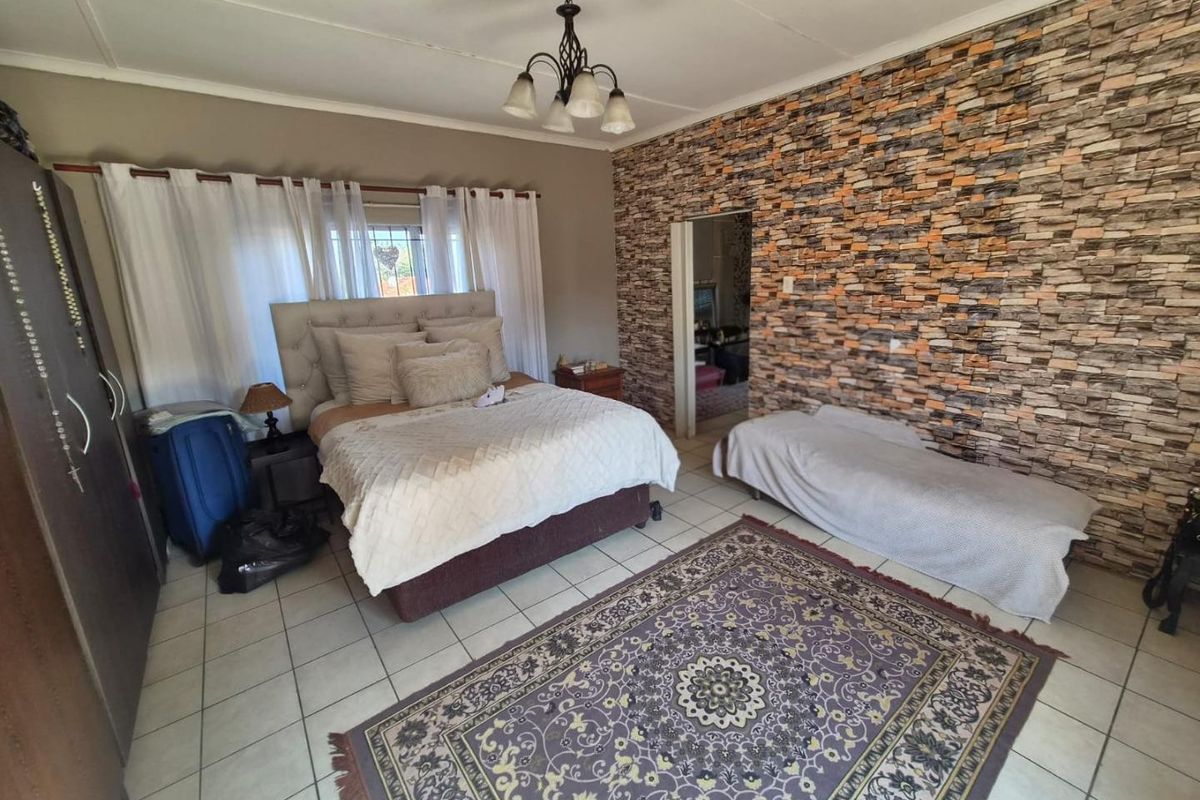 A bedroom featuring tiled flooring and a prominent stone-cladding feature wall, providing a textured focal point within the space.