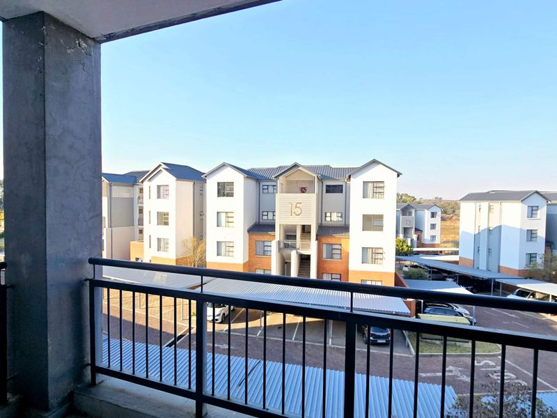A view from a balcony overlooking the apartment complex parking area and surrounding residential buildings.