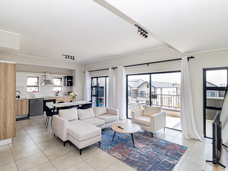 Spacious open-plan living area featuring a modern kitchen with built-in cabinetry, tiled floors, and large sliding doors leading to a private balcony.