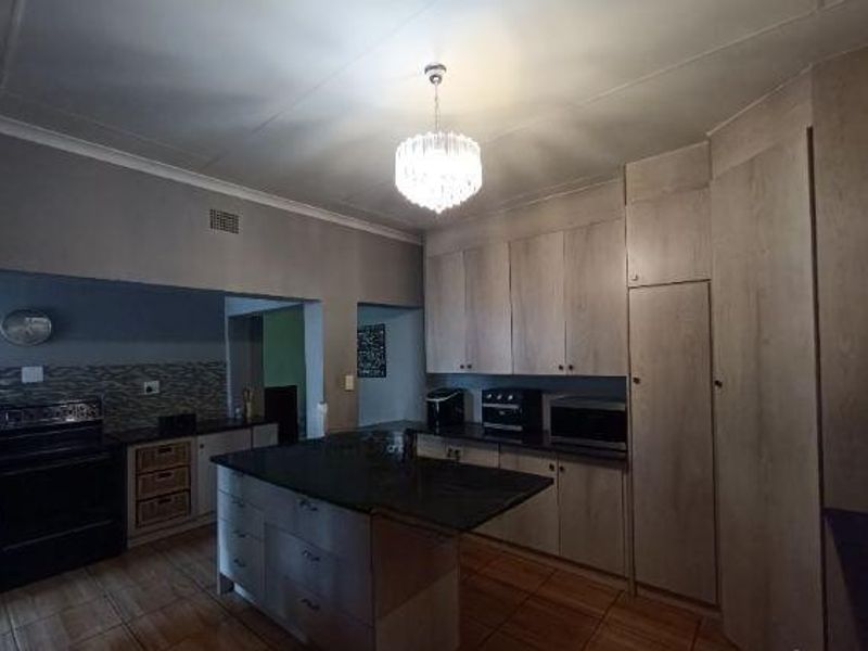 A functional kitchen featuring a central island with granite countertops, ample built-in cabinetry, and tiled flooring.