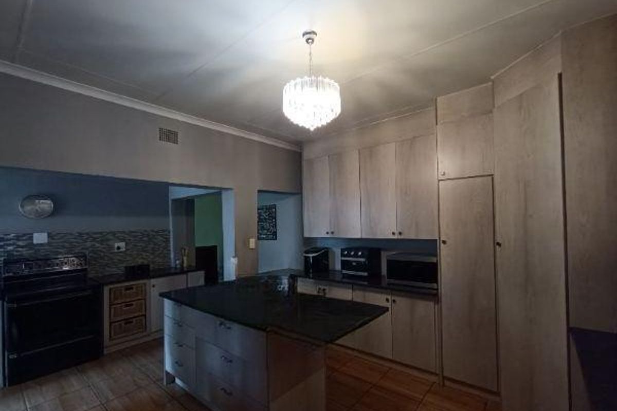 A functional kitchen featuring a central island with granite countertops, ample built-in cabinetry, and tiled flooring.